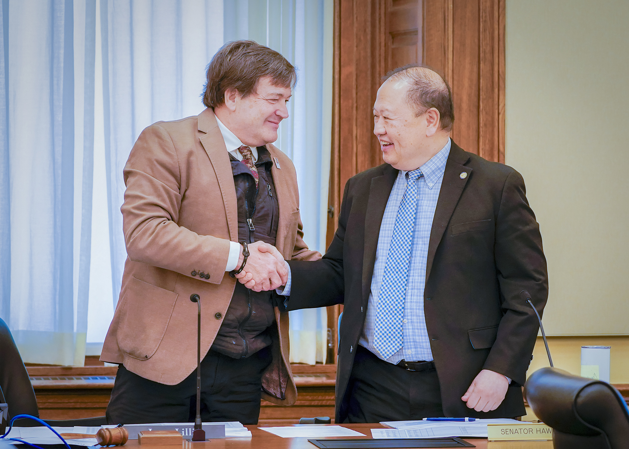 Rep. Leon Lillie and Sen. Foung Hawj shake hands after an agreement was reached, concluding the May 8 meeting of the legacy finance conference committee. (Photo by Andrew VonBank)